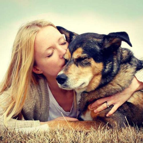 a lady kissing her old dog